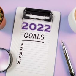 New year goals 2022 on desk. 2022 goals with open notebook, coffee cup on blue desk. Resolutions, plan, goals, action, idea concept. New Year 2022 template